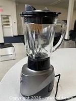 Full view of countertop blender showing silver base, glass pitcher, lid and power cord