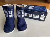 Front view of pair of navy Doctor Who TARDIS boot slippers and branded box