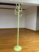 Full view of light green metal coat rack with round base and 8 arms