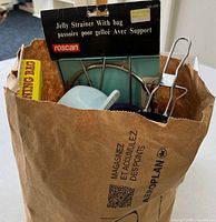 Paper bag with jelly strainer packaging and assorted utensils visible