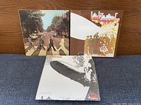 Front covers of Abbey Road, Led Zeppelin I (sealed), and Led Zeppelin II displayed upright on surface