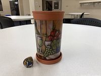 wine cooler with painted Mediterranean design and matching cork displayed on table