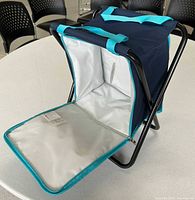 Cooler bag on black metal folding stool frame, main compartment open showing silver lining