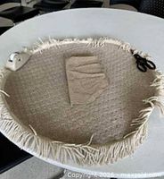 Top view of round beige rug with fringe and underpad placed on it