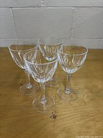 Four matching cut crystal wine glasses on wooden surface