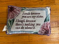 Front of rectangular embroidered pillow showing full text and floral design