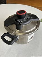 Angled view of T-fal Clipso 6 L stainless steel pressure cooker showing lid, handles and release valve