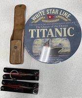 Titanic plaque, two folding travel hangers and leather pouch laid out for full view