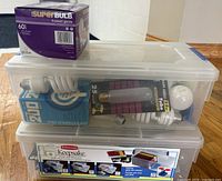 Stacked clear plastic containers filled with various packaged and loose light bulbs