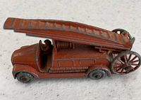 Side view of red Dennis fire ladder engine with ladder folded over body