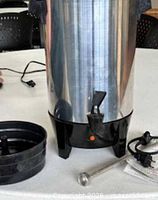 Coffee urn front view with drip tray, stem, cord, papers visible