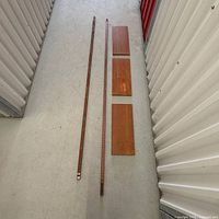 two teak support bars and three shelves laid out on floor