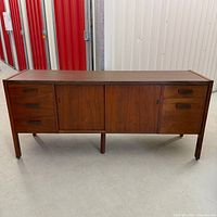 Full front view of walnut credenza showing drawers, sliding doors, legs