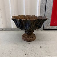 front view of cast iron urn showing scalloped rim and pedestal