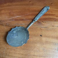 Full view of ornate 800 silver serving spoon on wood surface