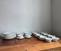 Stacks of plates, single-handle cups and two-handle bowls displayed on table