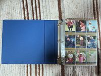 Open blue binder showing first 9 cards of the set in plastic sleeve
