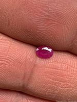Oval ruby on fingertip, showing size and color