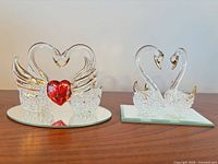 Both crystal swan figurine sets with mirrored bases displayed side by side
