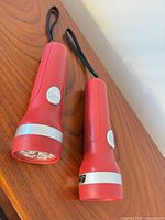 Two red Garrison LED flashlights side by side showing overall design and wrist straps