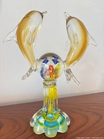 Front view of Murano glass dolphin figurine showing dolphins, globe, and pedestal