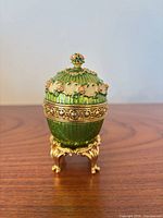 Closed green enamel egg on gold-tone stand