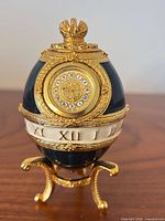 Front view showing egg clock, dial, gold accents, stand