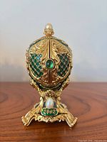Front view of green enamel egg on stand with 2002 plaque and cabochon