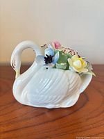 Front view of white bone china swan with colourful flower bouquet