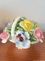 Front view of Royal Doulton bone china flower basket showing yellow and pink roses, blue bloom, basket handle
