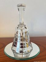 Full view of clear crystal bell showing etched design, silver bands and handle