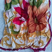 Close view of scarf corner showing floral pattern, fringe edge and Oscar de la Renta signature