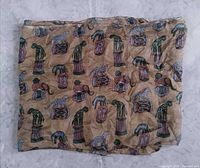 Scarf folded showing repeating cat pattern on beige fabric