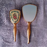 Front view of mirror and brush showing gold-tone handles and glass mirror