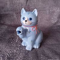 Front view of blue cat-shaped teapot showing paw spout and painted details