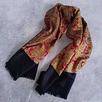 Full view of scarf showing red and gold paisley body and black fringed ends