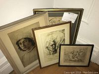 Photo showing five framed artworks grouped together leaning against a wall. Includes classical and original art pieces varying in size from around 9x10 to 19x14 inches. Visible wear on original drawing.
