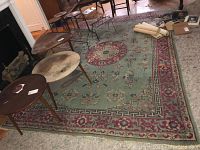 Full view of vintage area rug with furniture arranged on top showing floral and Greek key patterns.