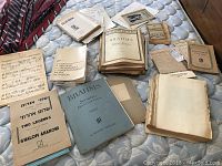 Overview of collection of vintage sheet music laid out on a mattress including Brahms, Beethoven, and other classical pieces.