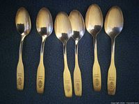 Six commemorative spoons laid out bowl up