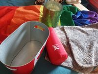 All five items grouped: rainbow throw, green vase, Canada tub, red emergency blanket, leaf pillow covers
