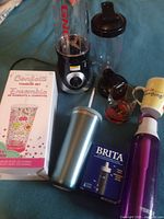 Overview showing Brita bottle, filter box, Bacardi glass, East Side Mario's mug, GNC blender set, confetti tumbler kit box and teal tumbler