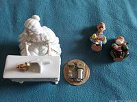 Top view showing porcelain woman at piano, detached music box base mechanism, two clay musician figurines