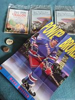 Group shot of poster, three books, token and bottle cap