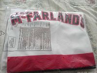 Folded white jersey in sealed bag, McFARLAND'S lettering and red hem visible