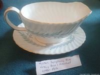 Overall view of gravy boat attached to underplate showing pattern and gold trim