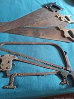 Three panel saws and two frame saws laid on blue surface