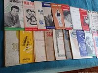 Overall view of approx. 20 sheet music pieces laid out, showing variety of titles and cover art