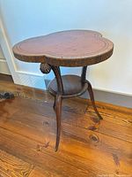 Overall view of wood tripod table showing clover-shaped inlaid top and three legs
