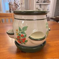 Full view of ceramic planter on saucer showing pockets and decals